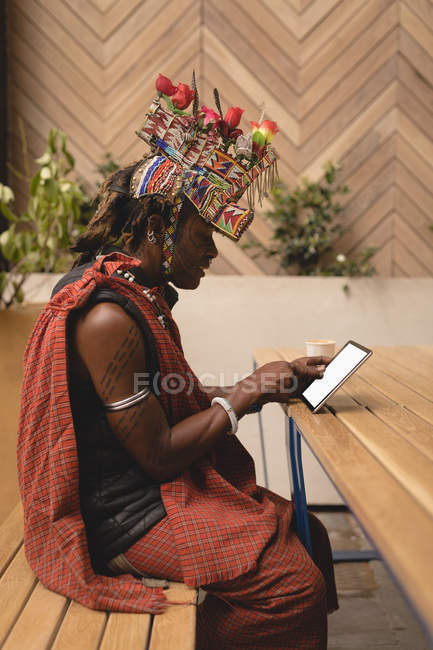 Hombre masai en ropa tradicional usando tableta digital en el restaurante - foto de stock