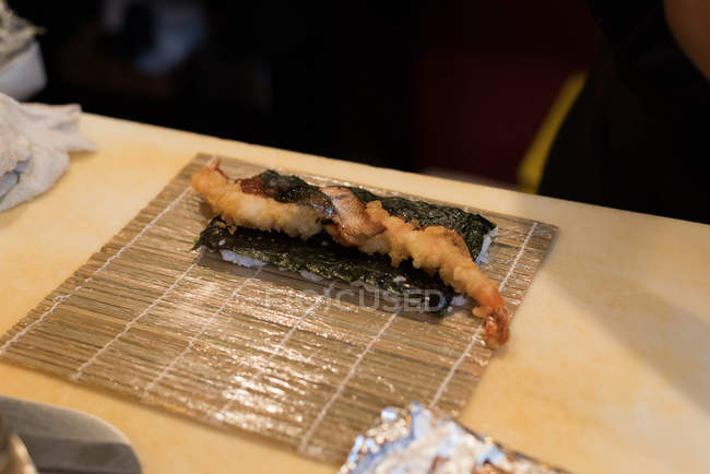 Развернутые суши с жареными креветками хранятся на кухонном столе в ресторане — стоковое фото