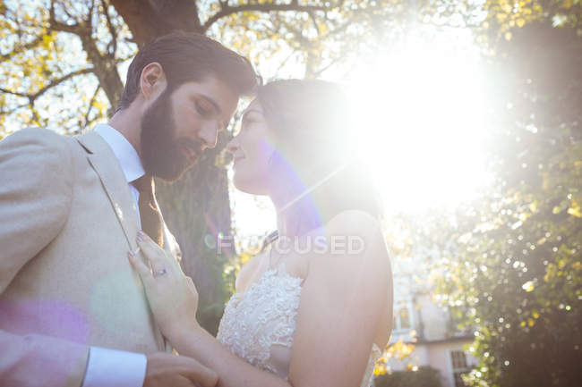 Romantic bride and groom standing face to face in the garden on a sunny day — Stock Photo