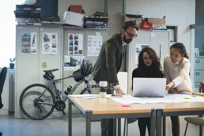 Executivos discutindo sobre laptop no escritório moderno — Fotografia de Stock