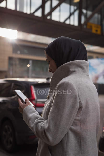 Woman in hijab using mobile phone on city street — Stock Photo
