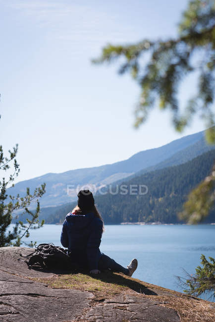 Female hiker sitting on rock near sea side — Stock Photo