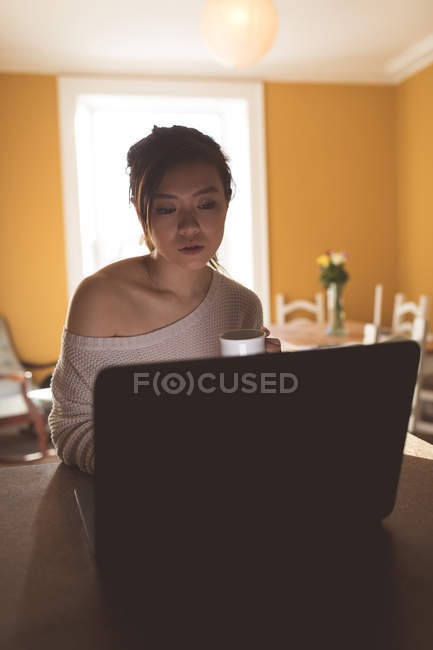 Giovane donna che utilizza il computer portatile a casa — Foto stock