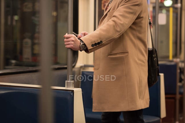 Secção média do homem que usa telemóvel enquanto viaja de comboio — Fotografia de Stock