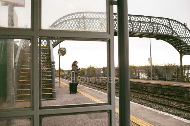 Donna in attesa del treno con i bagagli al binario — Foto stock