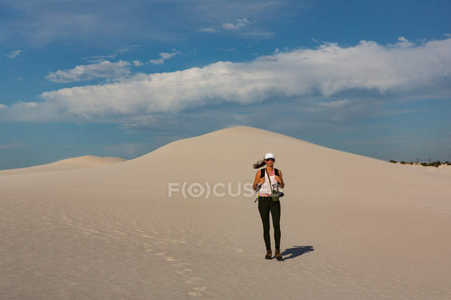 Caminhante feminina com mochila em pé na areia em um dia ensolarado — Fotografia de Stock