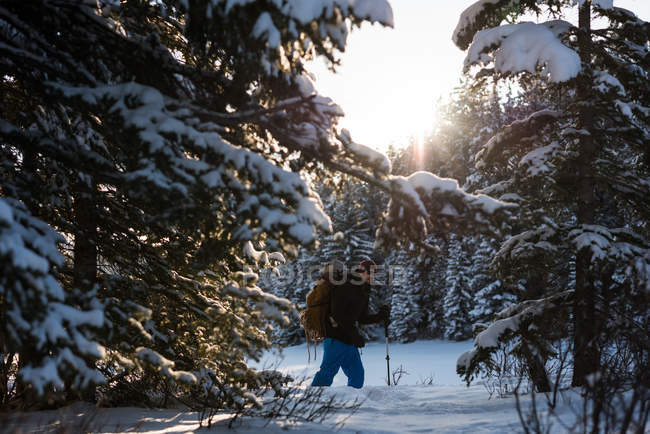 Чоловік сніжить з рюкзаком у засніженому лісі . — стокове фото