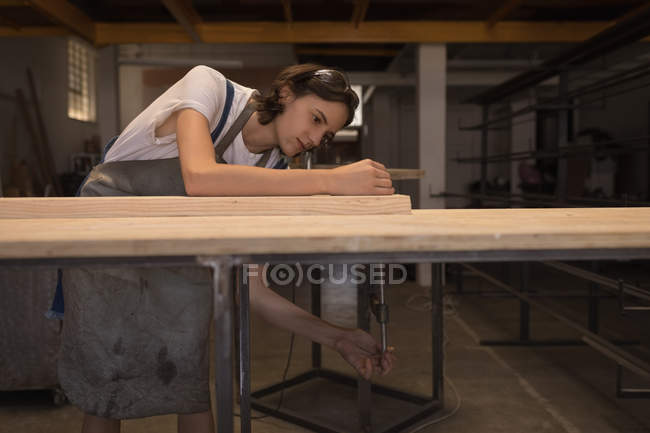 Junge Kunsthandwerkerin arbeitet in Werkstatt mit Holz. — Stockfoto