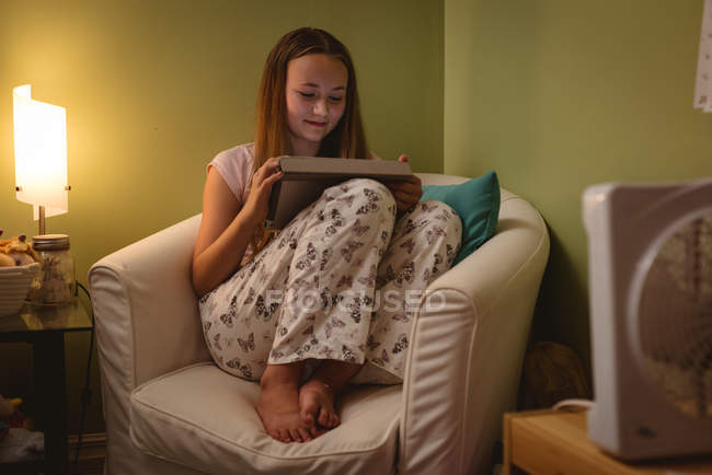 Mädchen liest Buch, während sie zu Hause im Sessel sitzt. — Stockfoto