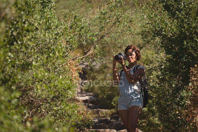 Женщина-туристка фотографируется с цифровой камерой в лесу на природе — стоковое фото