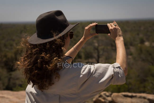 Mulher tirando foto com celular em um dia ensolarado — Fotografia de Stock