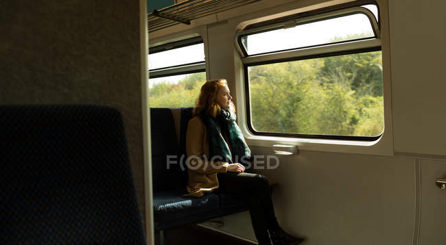 Задумчивая молодая женщина, путешествующая на поезде — стоковое фото