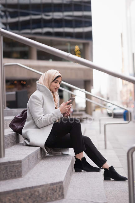 Жінка в хіджабі, використовуючи мобільний телефон на сходах — стокове фото
