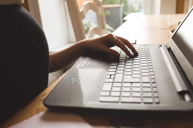 Sección media de la mujer que usa el ordenador portátil en casa - foto de stock