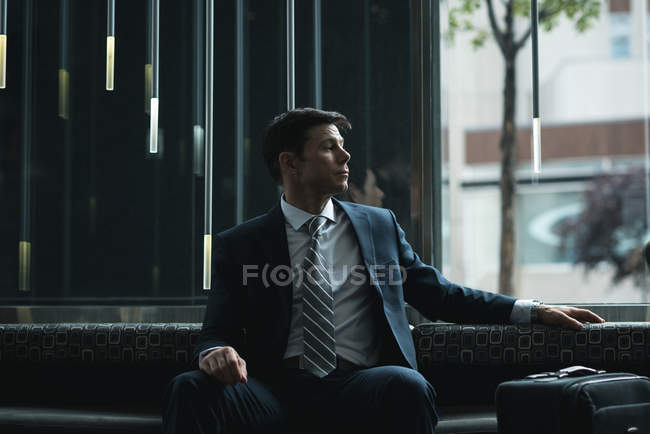 Homem de negócios atencioso sentado no sofá do hotel — Fotografia de Stock