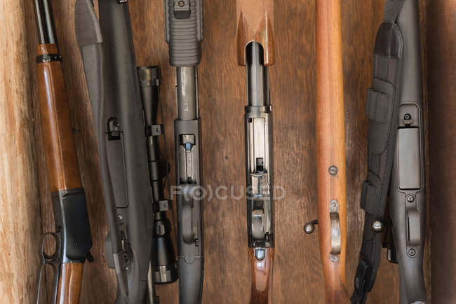 Primer plano de varias armas dispuestas en estante de madera - foto de stock