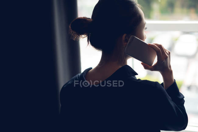 Vista trasera de la mujer hablando por teléfono móvil en la habitación del hotel - foto de stock