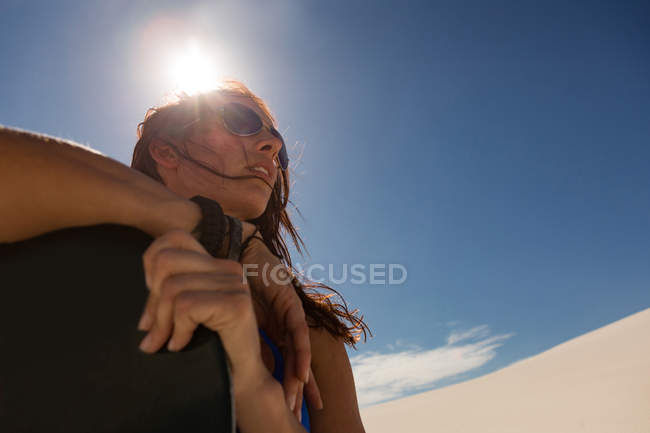 Frau mit Sandbrett steht an einem sonnigen Tag in der Wüste — Stockfoto