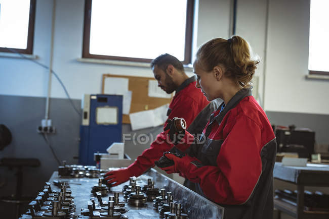 Двоє робітників перевіряють деталі машини на заводі — стокове фото