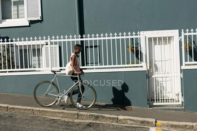 Woman waking with bicycle on a sidewalk in city — Stock Photo