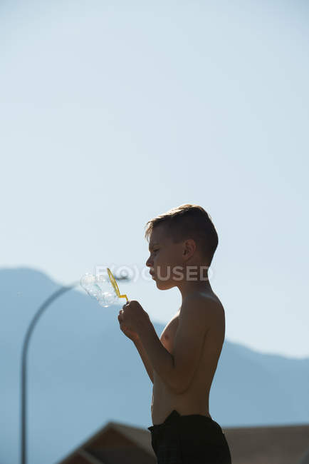 Boy playing with bubble wand on a sunny day — Stock Photo