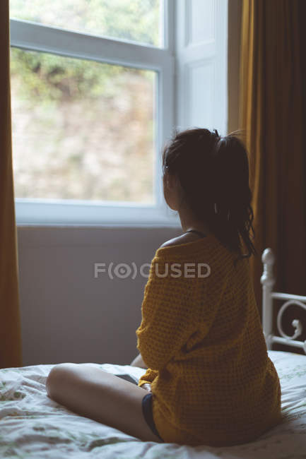 Thoughtful woman relaxing in bedroom at home — Stock Photo