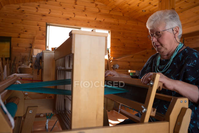 Mulher sênior ativa tecendo seda na loja — Fotografia de Stock