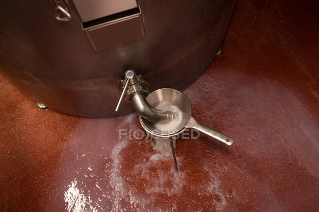 Líquido filtrado e transbordando do tanque na fábrica de alimentos — Fotografia de Stock