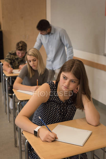 Pensativo adolescente sentado en el aula en la universidad - foto de stock