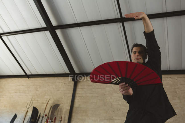 Uomo che pratica con fan di kung fu in palestra
. — Foto stock