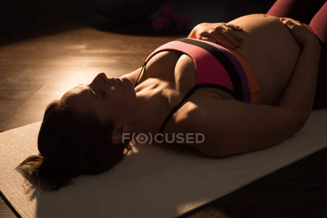 Беременная женщина медитирует, прикасаясь к животу — стоковое фото