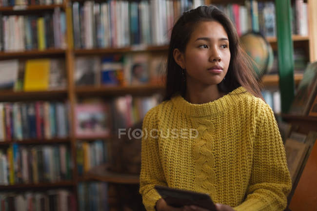 Nachdenkliches Teenager-Mädchen nutzt digitales Tablet in Bibliothek — Stockfoto