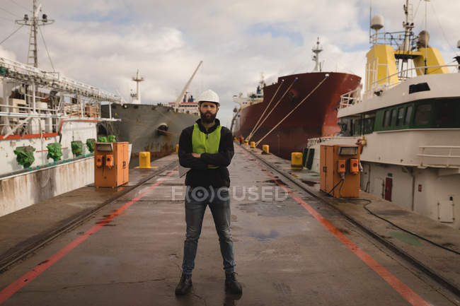 Portrait of dock worker standing with arms crossed in shipyard — Stock Photo