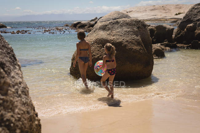 Frères et sœurs marchant avec balle dans la mer à la plage — Photo de stock
