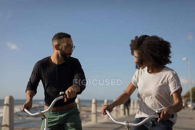 Романтическая пара, смотрящая друг на друга, наслаждаясь велосипедной прогулкой в солнечный день — стоковое фото