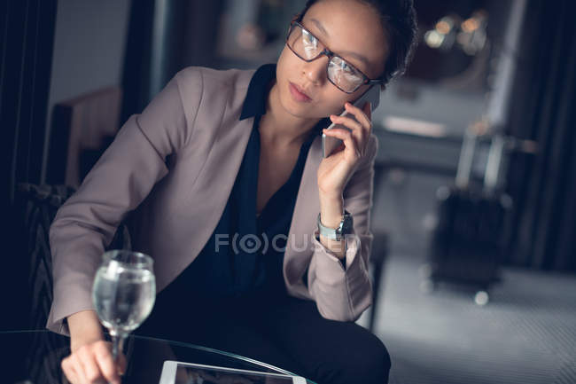 Mujer hablando por teléfono móvil mientras toma vino - foto de stock