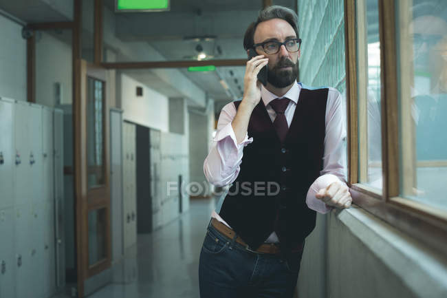 Исполнительный разговор по мобильному телефону в офисном коридоре — стоковое фото