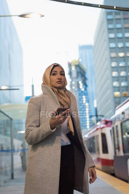 Mulher no hijab usando telefone celular na estação ferroviária — Fotografia de Stock