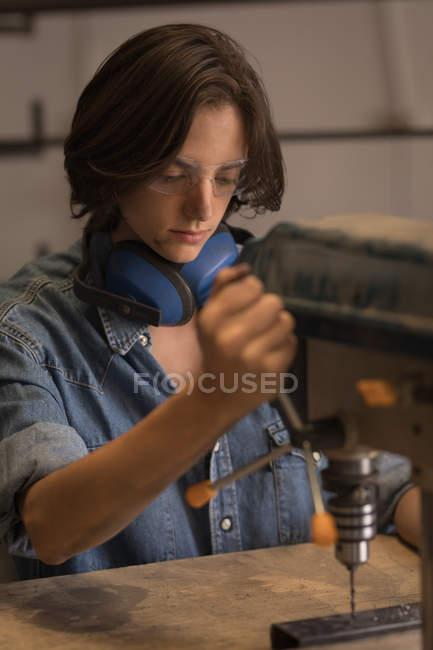 Artigiano femminile utilizzando perforatrice verticale in officina
. — Foto stock