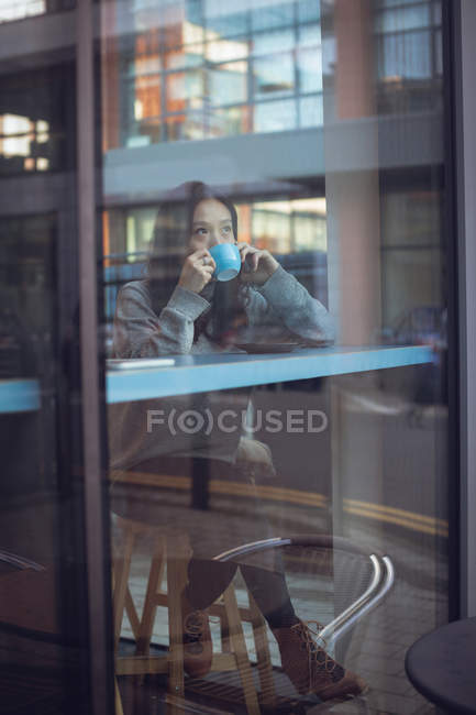 Bella donna che parla al telefono cellulare mentre prende un caffè in mensa — Foto stock