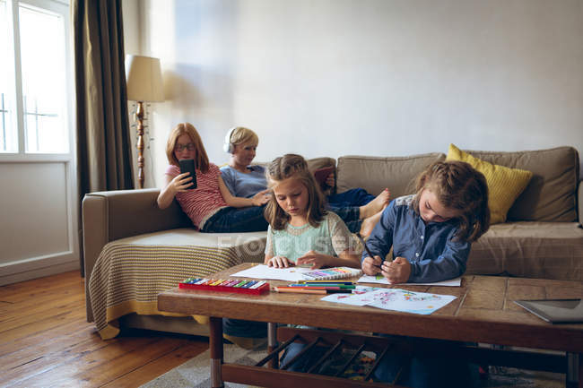 Сестри роблять домашнє завдання у вітальні вдома — стокове фото