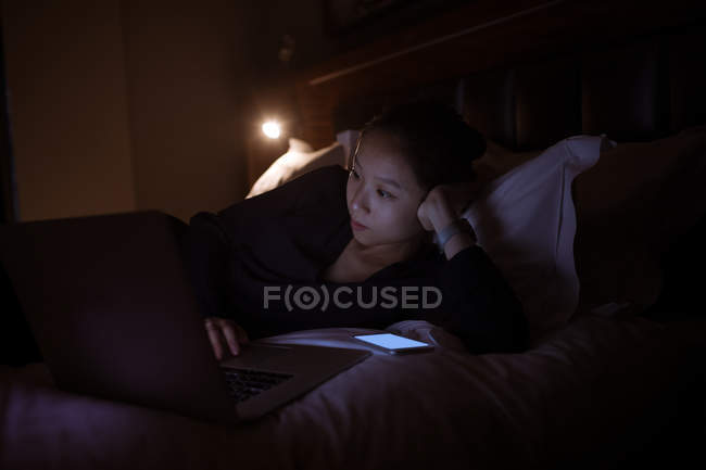 Woman using laptop on bed in hotel — Stock Photo