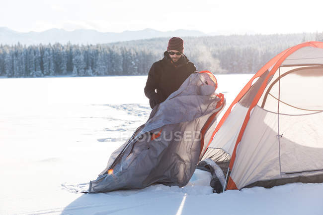 Mann schlägt im Winter sein Zelt in verschneiter Landschaft auf. — Stockfoto