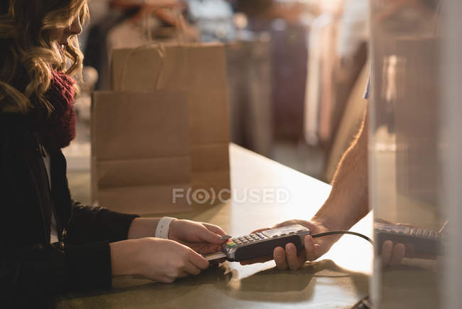 Chica haciendo el pago a través del teléfono móvil en el mostrador - foto de stock