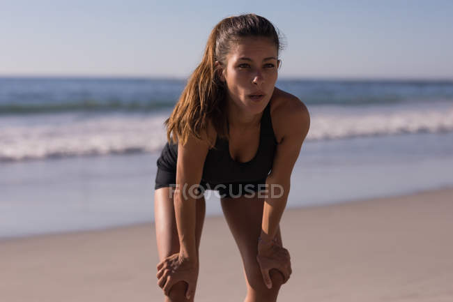 Втомлена жінка-спортсменка робить перерву на пляжі в сутінках . — стокове фото
