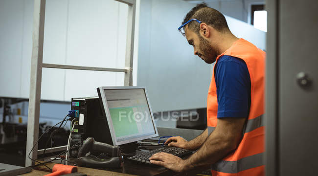 Trabajador masculino que trabaja en la computadora en fábrica - foto de stock
