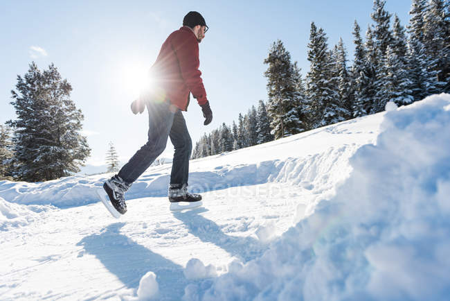 Mann Schlittschuhlaufen in verschneiten Wäldern im Winter, niedriger Winkel Blick. — Stockfoto