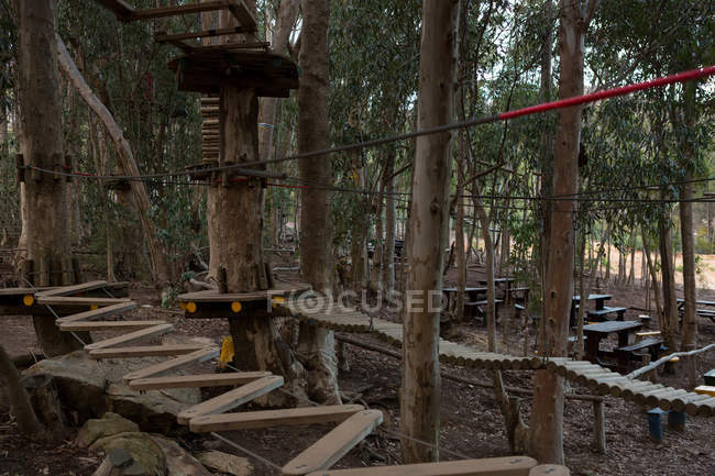 Los obstáculos de madera del curso de cuerdas en el bosque - foto de stock