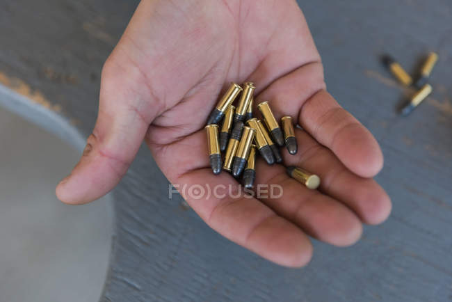 Close-up of man holding bullets in hand — Stock Photo