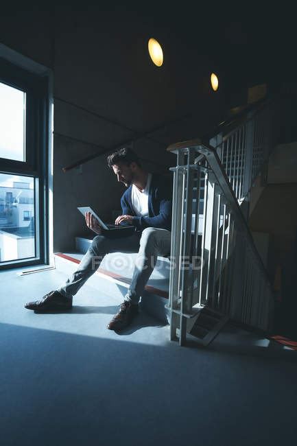 Executivos usando laptop em escadas no escritório moderno — Fotografia de Stock